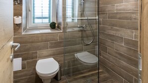 Ein modernes Badezimmer mit einer gläsernen Dusche, einer Toilette und einem Waschbecken.
