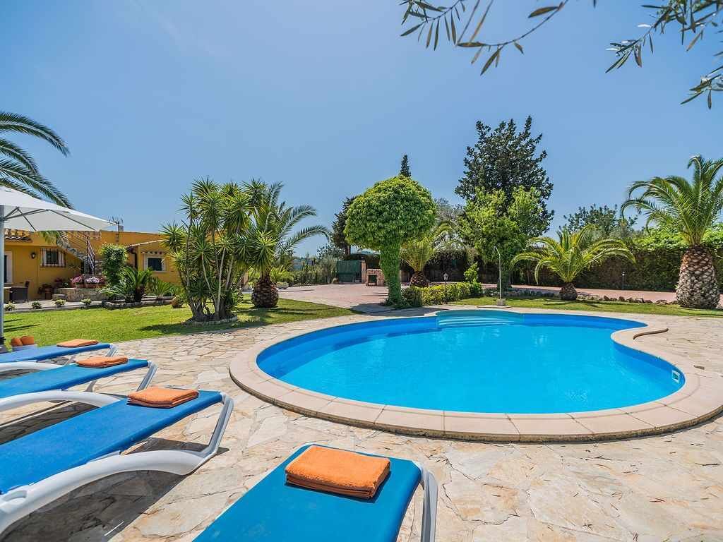 Una piscina con sillones de descanso y un jardín bien cuidado.