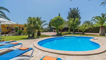 En swimmingpool med liggestole og en velplejet have.
