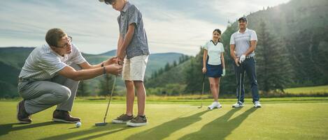 A golf course with a group of people, including a child, on the putting green.