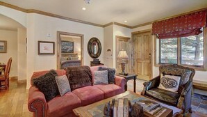 Una sala de estar acogedora con un sofá rojo, una mesa de centro de madera y un sillón de cuero.