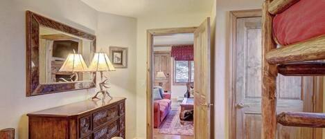 A cozy room with a wooden dresser, a mirror, and a bed with a red blanket.