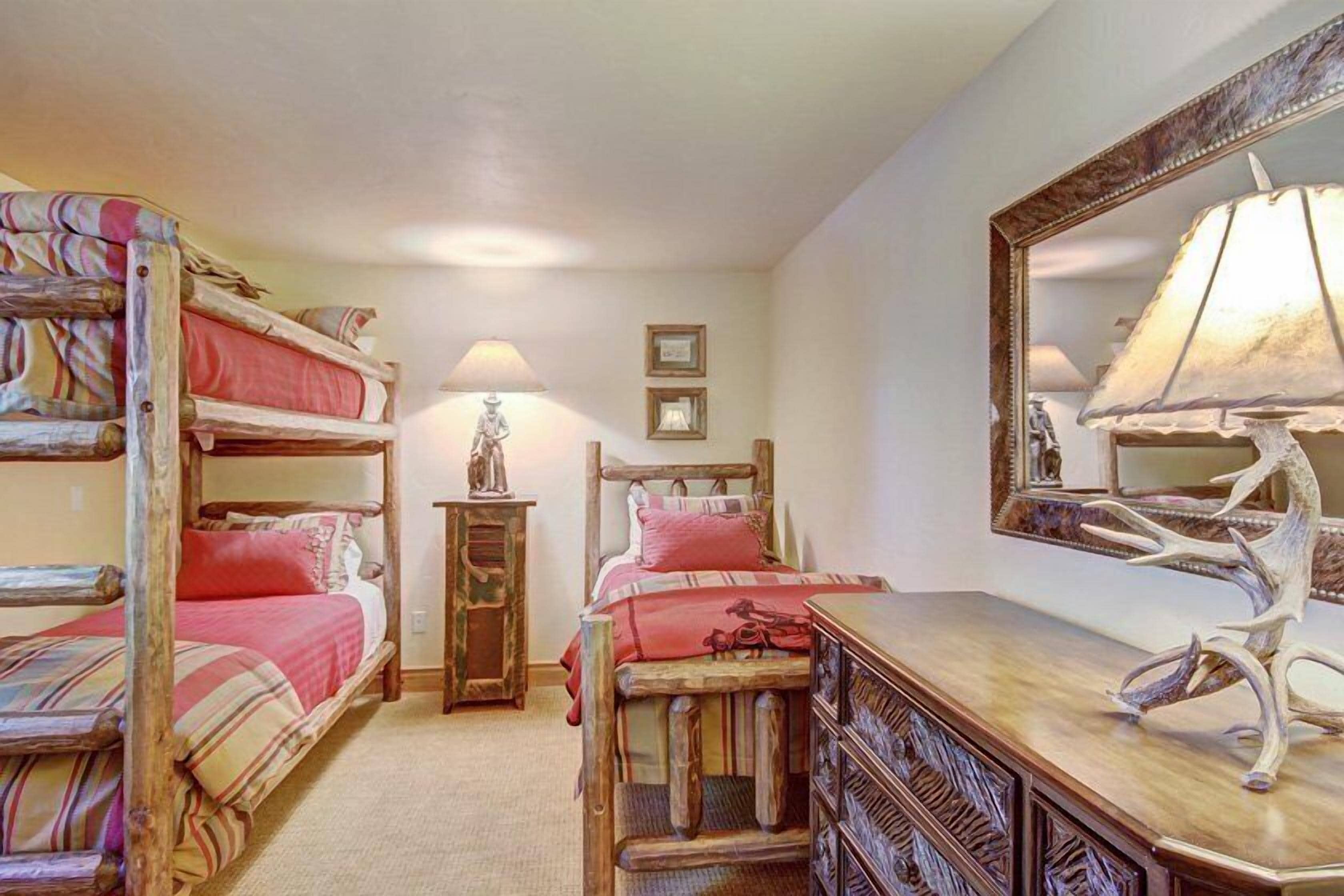 A room with bunk beds, a wooden dresser, a mirror, and a lamp.