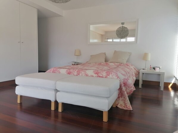 A bedroom with a bed, two bedside tables, a mirror, and a bench.