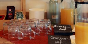 A beverage station with clear mugs, a sign for orange salt, and a pitcher of orange juice. - Landhotel Buchenkrug (Halle Westphalia)