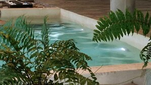 A modern indoor pool area with a stone border, a water feature, and two lit candles. - Los Robles Apart Hotel (Sierra de la Ventana)