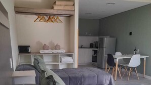 A modern bedroom with a large bed, a kitchenette, and a dining area. - Los Robles Apart Hotel (Sierra de la Ventana)