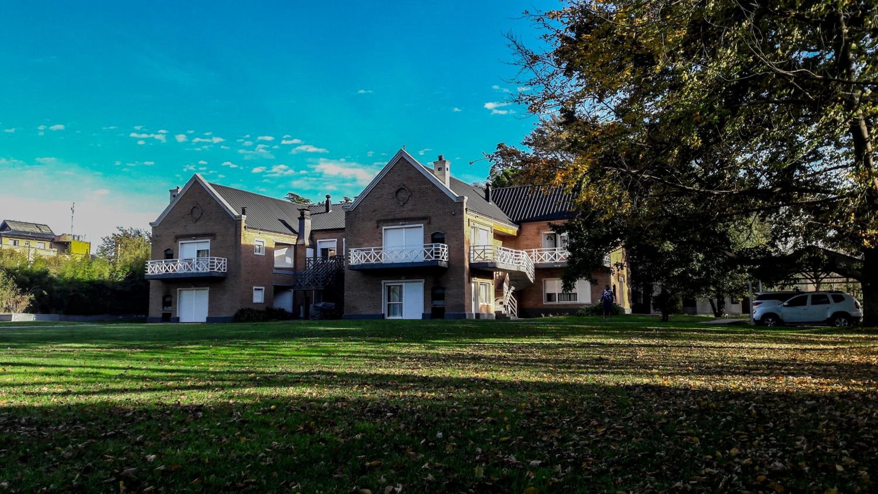 A two-story house with a front lawn and a tree to the right.