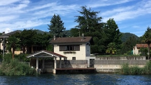 A house by a river with a small dock and a covered seating area. - LA PLAYA: Villa with a Private Beach and All-Inclusive Sports  (Pettenasco)