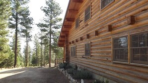 Une cabane en rondins avec une allée en gravier et une bordure en pierres.