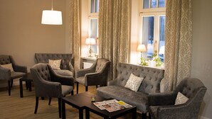 Ein Wohnzimmer mit Sofa, Sesseln, Couchtisch und Lampe.