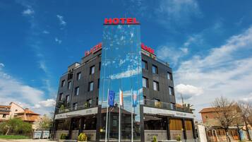 Experience the vibrant atmosphere of the city at Platinum Hotel, where a striking glass facade and prominent sign welcome you.