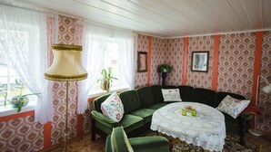 A cozy room with a green sofa, a lace table, and patterned wallpaper. - Handelsstedet Forvik (Vevelstad)