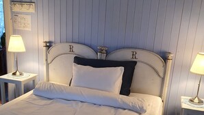 A neatly made bed with white linens, two bedside tables with lamps, and a blue paneled wall. - Handelsstedet Forvik (Vevelstad)