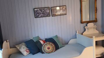 A room with a white bed, a small table, and a mirror on the wall.