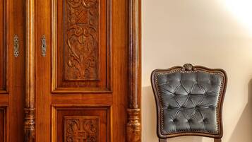 A wooden cabinet with intricate carvings and a velvet-upholstered chair with a tufted backrest.