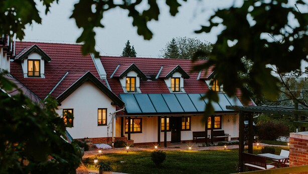 A house with a red roof, multiple windows, and a covered patio area. - Kosbor Panzió (Magyarszombatfa)