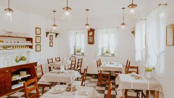 A dining area with multiple tables and chairs, wooden cabinets, and hanging light fixtures.