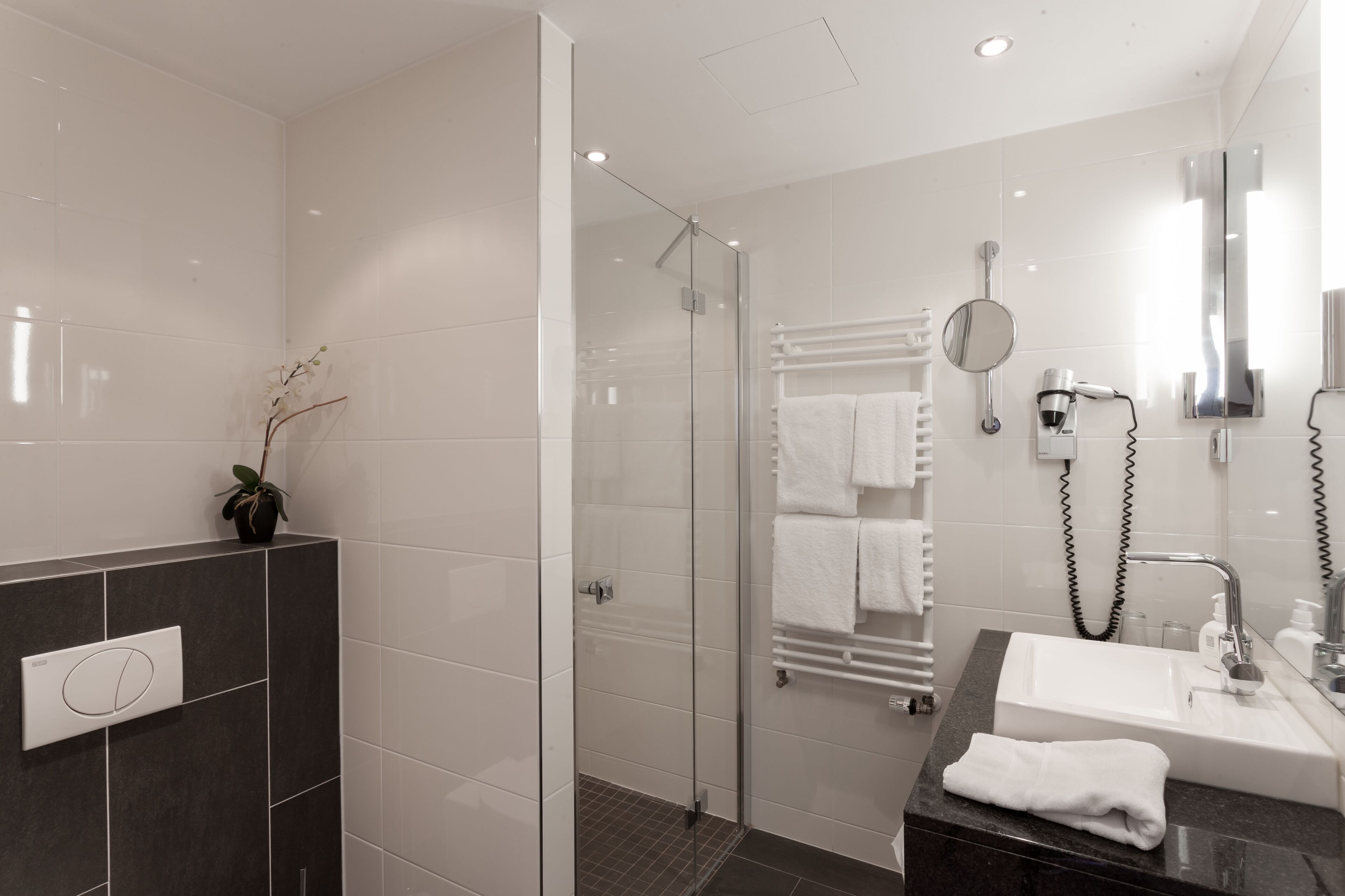 A modern bathroom with a glass-enclosed shower, a vanity with a sink, and a towel rack.
