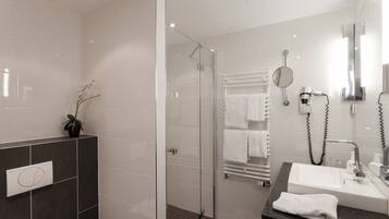 A modern bathroom with a glass-enclosed shower, a vanity with a sink, and a towel rack.