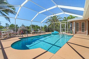 A pool area with a covered section, lounge chairs, and a water slide.