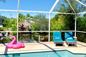 A pool area with a clear view of the pool, lounge chairs, and a decorative flamingo float.