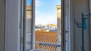 A window with a view of a tiled roof and buildings in the distance. - Cozy Studio Near Beach and Downtown (Les Sables-d'Olonne)