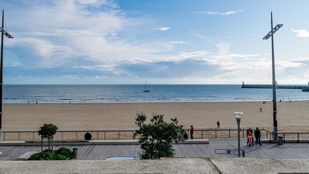 A beach with a promenade, a lighthouse in the distance, and a clear sky. - Cozy Studio Near Beach and Downtown (Les Sables-d'Olonne)