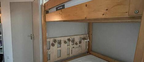 A bunk bed with two levels, each labeled "NIGHTTIDE." The room has a wooden floor and a white door.