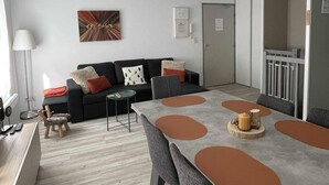 Una sala de estar moderna con una mesa de comedor, sofá y un cuadro en la pared.