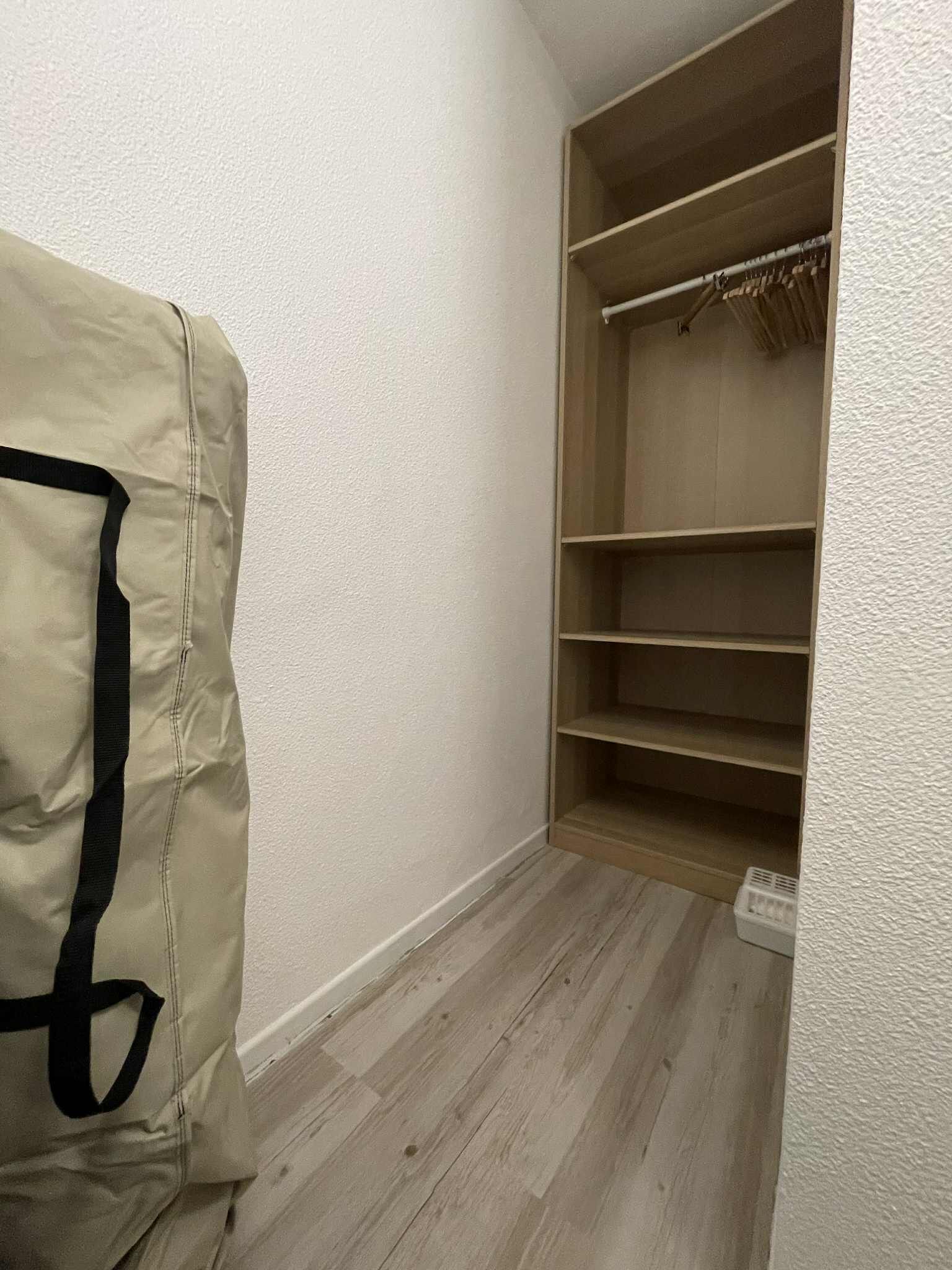 A corner of a room with a wooden closet and a beige bag on the floor.