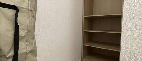 A corner of a room with a wooden closet and a beige bag on the floor.