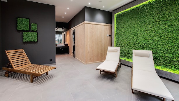 Uma área de spa moderna com espreguiçadeiras de madeira e uma parede verde.