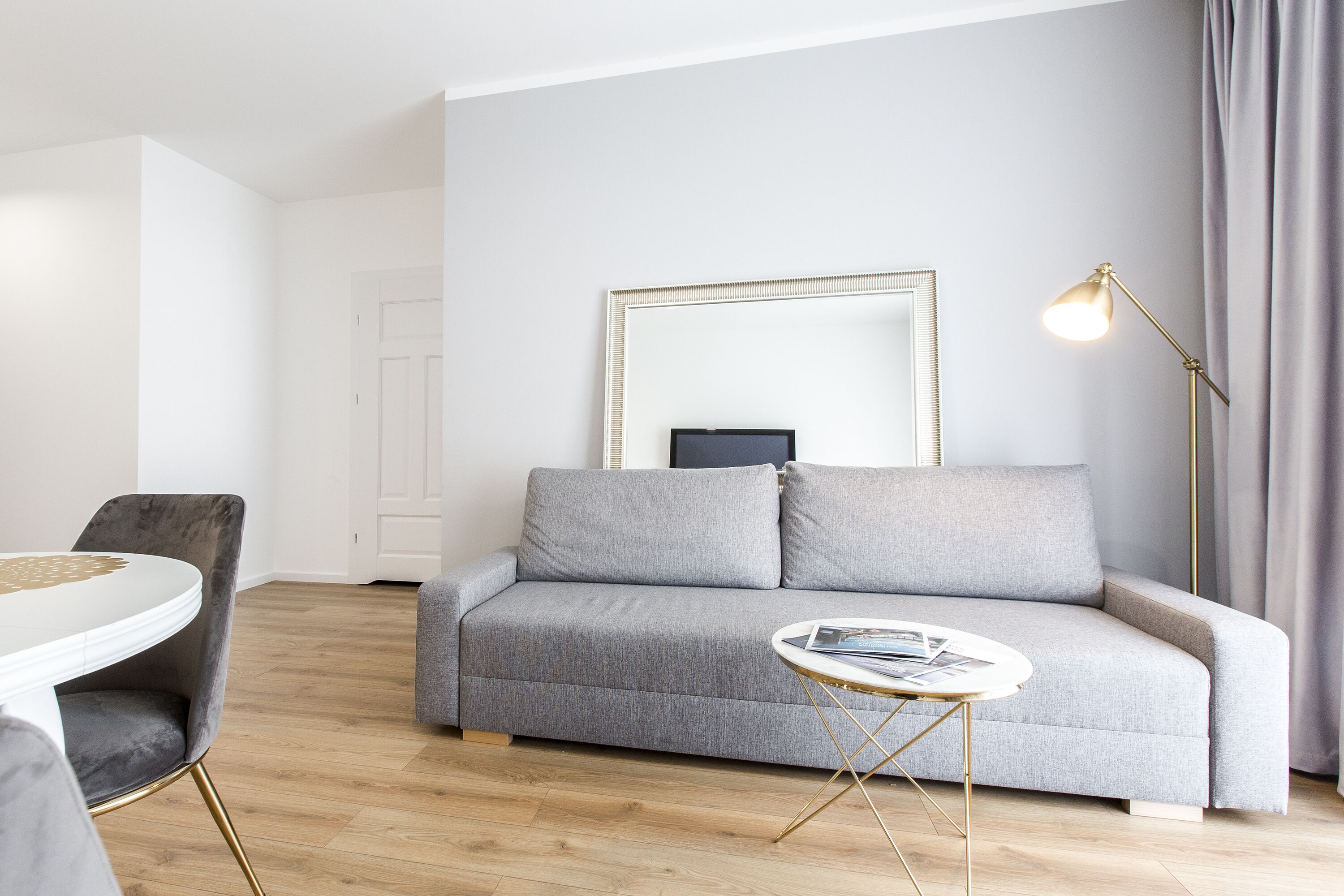 A modern living room with a grey sofa, a round coffee table, and a floor lamp.