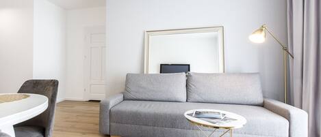 A modern living room with a grey sofa, a round coffee table, and a floor lamp.