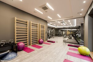 A gym with exercise equipment, treadmills, and a mirrored wall.