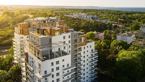 Um edifício residencial alto, com várias varandas e um terraço no telhado.