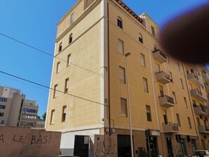 Un immeuble à plusieurs étages doté de balcons, avec une entrée au rez-de-chaussée bien visible et un panneau indiquant un espace de stationnement.