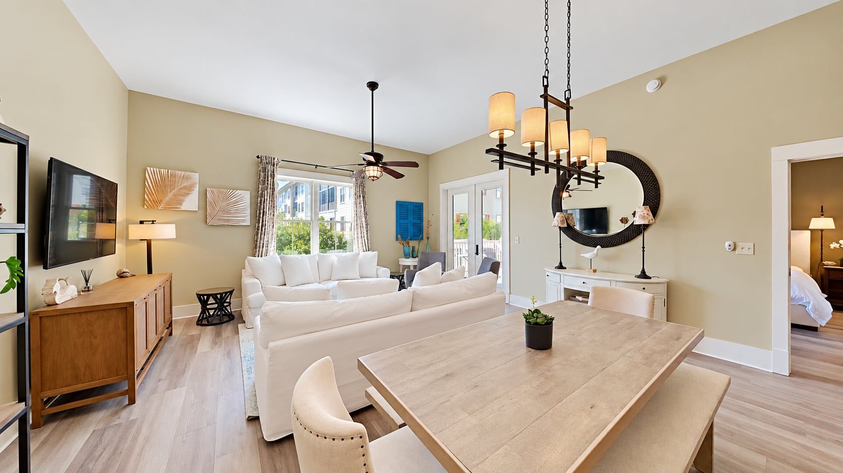 A modern living room with a dining area, a ceiling fan, and a large mirror.