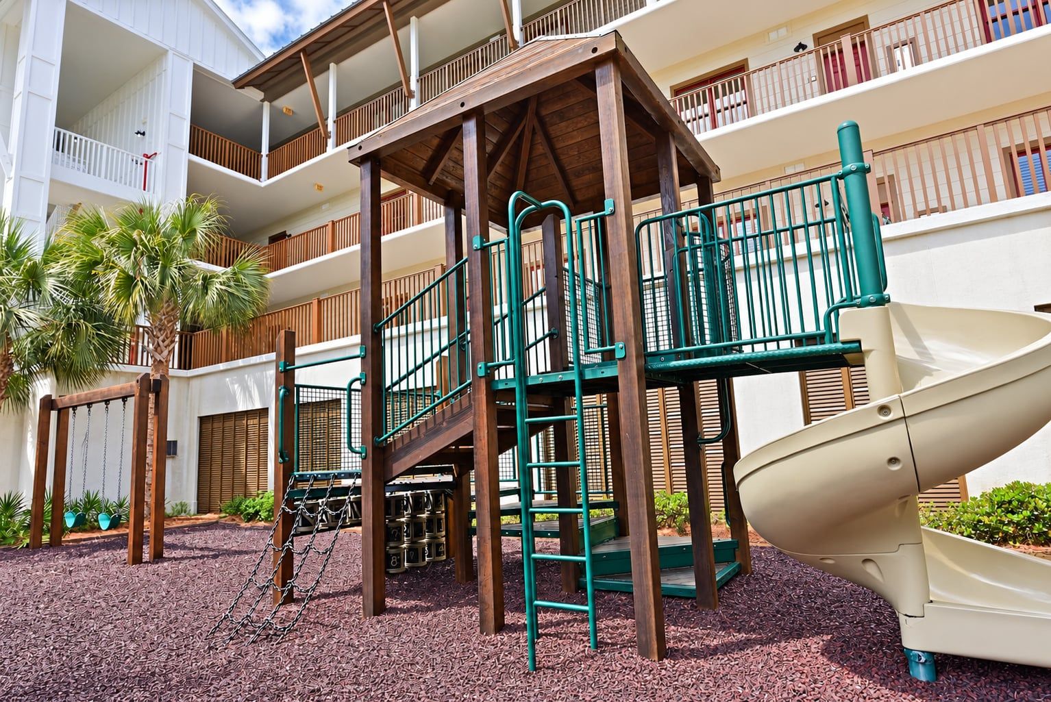 A playground with a slide, climbing structures, and a wooden playhouse.