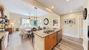 A modern kitchen with a central island, wooden cabinets, and a built-in dishwasher. - Vitamin Sea - 3BR/3BA Redfish Village Condo - Sleeps 9 - Deeded Beach Access (Santa Rosa Beach)