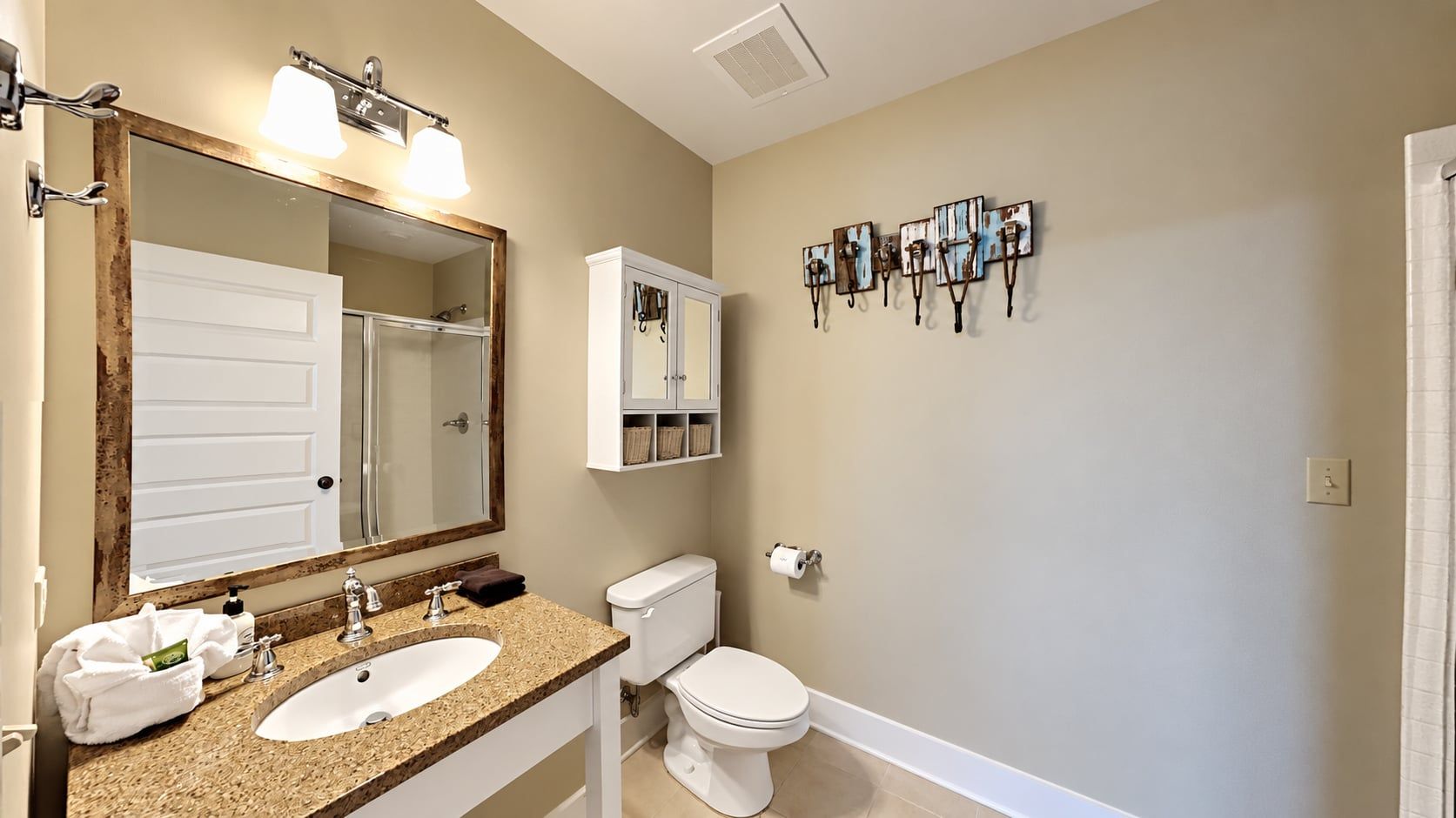 A bathroom with two sinks, a toilet, a mirror, and a wall-mounted towel rack.