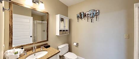 A bathroom with two sinks, a toilet, a mirror, and a wall-mounted towel rack.