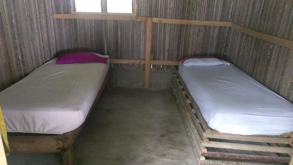 Una habitación pequeña y rústica con dos literas de madera, cada una con colchón y almohada.