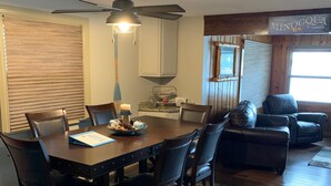 Uma sala de jantar com uma mesa de madeira, cadeiras e um ventilador de teto.