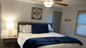 Quarto com cama, mesa de cabeceira, abajur, ventilador de teto e placa indicando 'Zona sem Perturbação'.