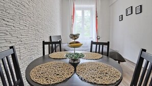 A dining area with a round table, black chairs, woven placemats, and a fruit centerpiece. - Dream Apartments Rzeszowska (Kraków)