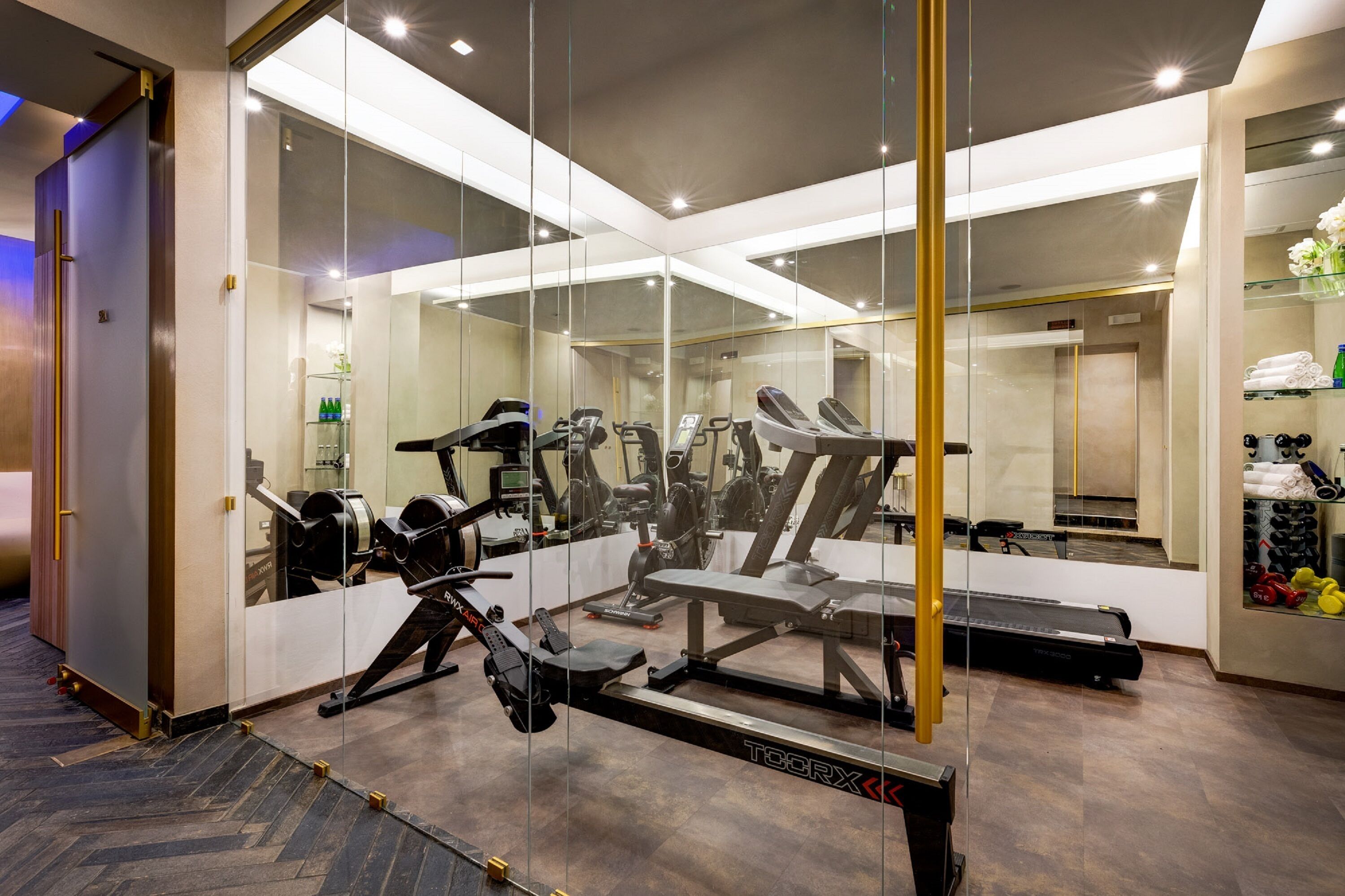A modern gym with various exercise equipment, a treadmill, and a mirrored wall.