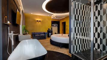 Un baño moderno con una bañera independiente, cabina de ducha y una cama decorada con pétalos de rosa.