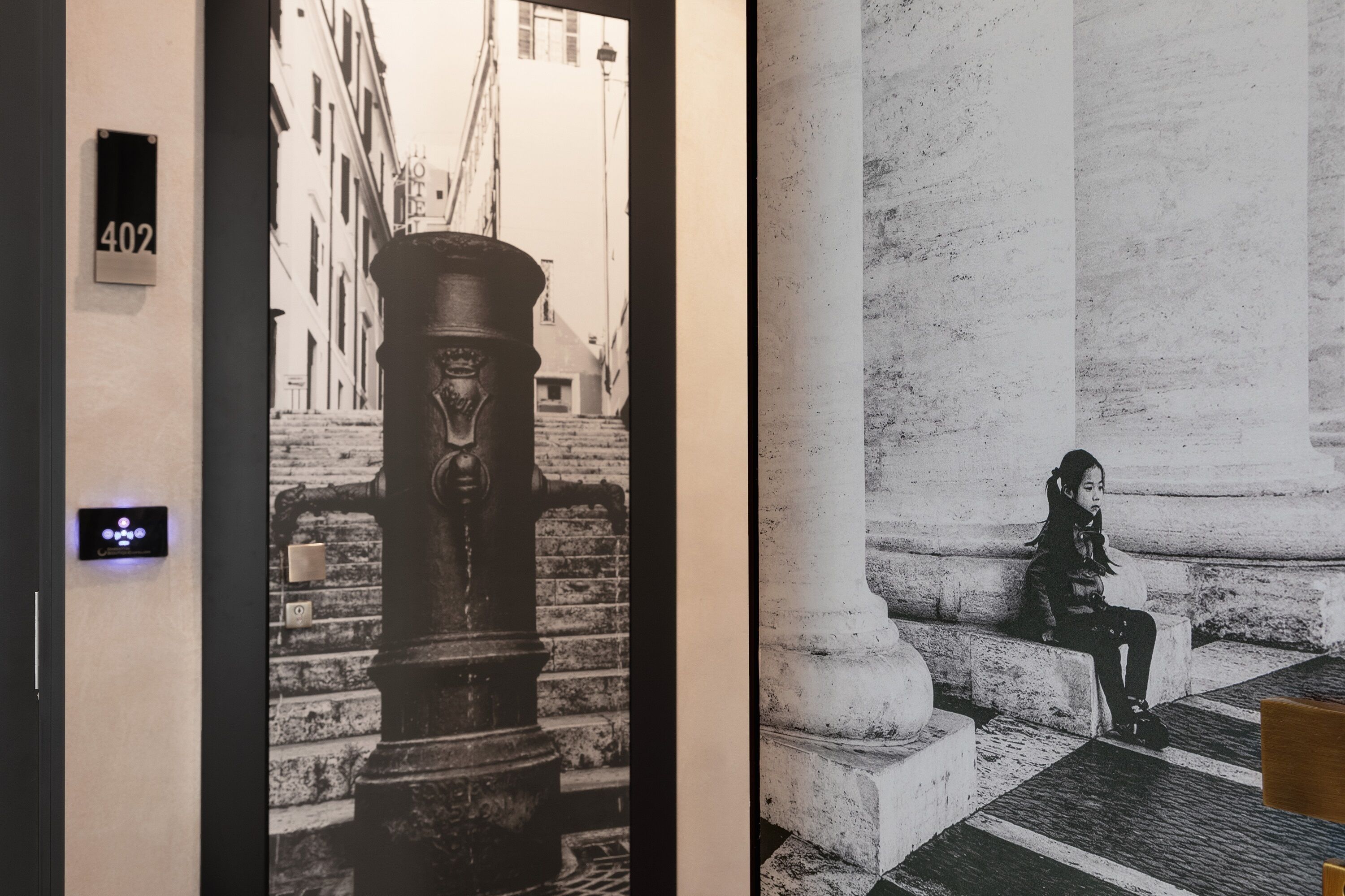 A hallway with a door labeled "402" and a black and white photograph of a woman sitting on steps.